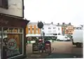 The building on extreme left foreground (the one where the sign is cut off to read " 'hop".) apparently has, on its Market Place-facing side, musket ball holes which date from the English Civil War. It was built in 1570. The muskets were fired from the castle, which stood on the other side of the Market Place, roughly where that row of buildings in the background stands.