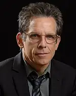 A headshot of a man with gray hair and glasses