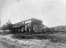 Black and white photo of a small brick house between fields of crops