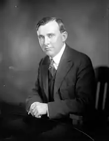 Black and white portrait of a man in a suit sitting in a chair.