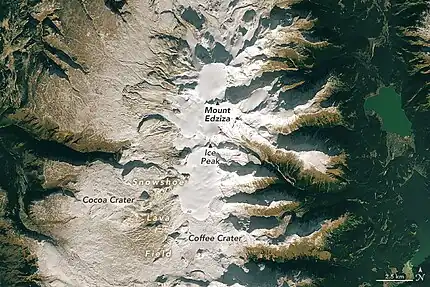 An overhead view of a barren, lightly snow-covered plateau with a glaciated mountain in the middle.