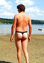 A man in a black thong swimsuit