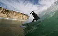 A surfer at Black's, with cliffs in background