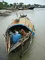 Bangladeshi fishermen resting in the shade of a sampan in Barishal