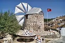 Round stone building with a circle of triangular sails, and in the distance a red flag with white crescent and star