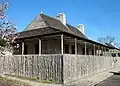 View of typical stockade fence; also view of side and front of house