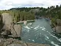 A stream of water in front curving around some large boulders