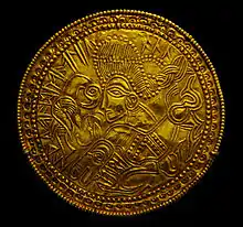 A Migration Period Germanic gold bracteate featuring a depiction of a bird, horse, and stylized head wearing a Suebian knot.