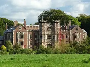 Red brick house with taller gatehouse and a hedge in front