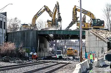 A bridge being demolished by four excavators