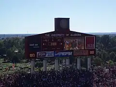 Large scoreboard in an American football stadium surrounded by crowded stands.