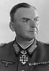 A man wearing a military uniform with an Iron Cross displayed at the front of his uniform collar.