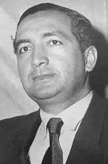 Black-and-white portrait of a man in semi profile wearing a suit and tie.