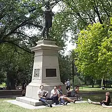 statue of man on a tall base in a park