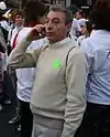 A man wearing a turtleneck shirt is holding a cellphone