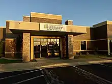 The front of the Nixa branch library is depicted. The library is brick and immediately meets a parking lot.