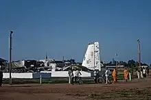 A damaged plane and a military vehicle on display on plinths in the open air