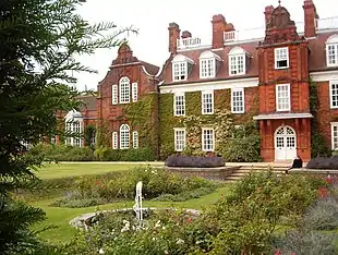 Large, red-brick three-story building; there is a sunken ornamental garden in front.