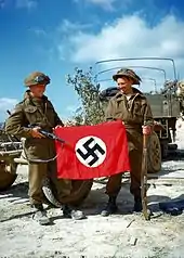 Canadian soldiers during Operation Overlord showing a captured Nazi flag as a war trophy outside Hautmesnil, France in August 1944.Photo: National Archives of Canada