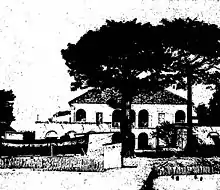 A large building in the background with the silhouettes of two trees in the foreground