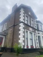 A large brick house with a sign on the side. The sign has the Coca-Cola logo and the words "Casbah Coffee Club".