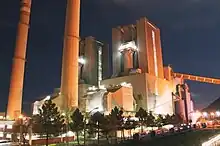 two tall chimneys and large buildings lit up at night