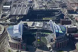 Two stadiums in an industrial area. Both have roofs with large arched trusses.