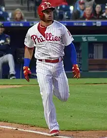 A baseball player in a white uniform with red pinstripes