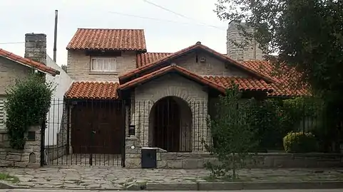 Typical vault-shaped porch on front, false front gable, attached garage with dormer on top and  chimney