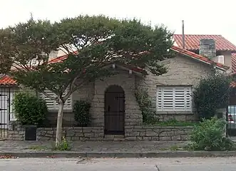 Yet another example featuring a vault-shaped, stone cladded porch on front with false gable hidden by a tree top and false chimney