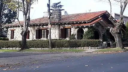 A full stone-cladded chalet with a rectangular, long layout and "embedded" portico-style porch