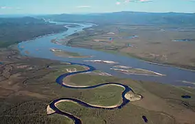 Aerial photo of the narrow horseshoe-bent Charley River flowing into the wide Yukon river with islands in the middle and nearby lakes