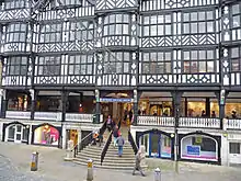 There are shops on the street level with wide steps leading to the first floor where there on more shops on the Rows. Above this are 2+ storeys in black-and-white architecture.