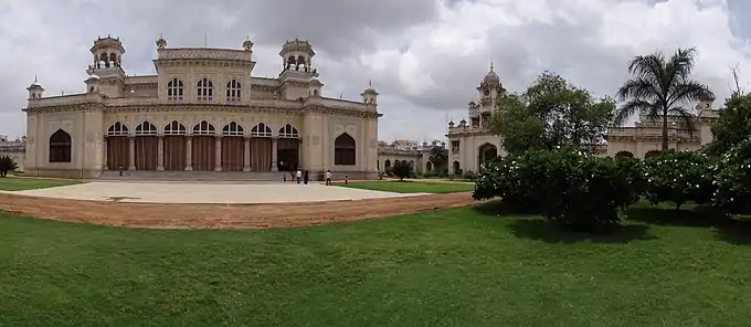 Single-story colonnaded façade with grass and trees in front