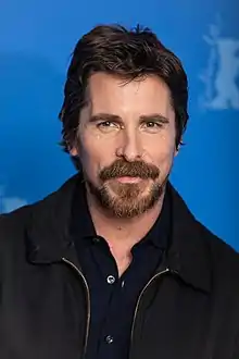 A headshot of Bale smiling on the red carpet at the 2019 Berlin International Film Festival