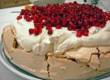 A pavlova garnished with pomegranates and cream