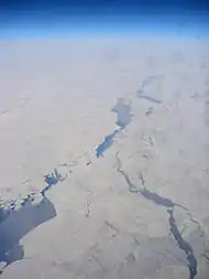 Aerial view of the Chukchi Sea between Chukotka and Alaska, displaying a pattern of leads. Much of the open water inside those leads is already covered by new ice (indicated by a slightly lighter blue color)(scale not available).