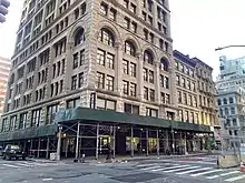 The lower stories of the building as seen from Broadway and Duane Street. The sidewalk is covered by scaffolding.