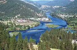 A wide river flows through coniferous forest in a mountain valley