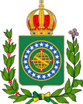 Coat of arms consisting of a shield with a green field with a golden armillary sphere superimposed on the red and white Cross of the Order of Christ, surrounded by a blue band with 19 silver stars; the bearers are two arms of a wreath, with a coffee branch on the left and a flowering tobacco branch on the right; and above the shield is an arched golden and jewelled crown