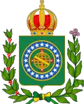 Coat of arms consisting of a shield with a green field with a golden armillary sphere superimposed on the red and white Cross of the Order of Christ, surrounded by a blue band with 20 silver stars; the bearers are two arms of a wreath, with a coffee branch on the left and a flowering tobacco branch on the right; and above the shield is an arched golden and jeweled crown.