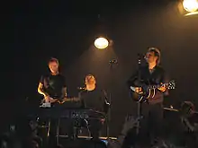 Three men on stage playing instruments