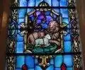 Small stained glass window, showing lion lying down with lamb