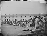 A contraband school, held outdoors. Note teacher, in coat and tie, on mound at left.