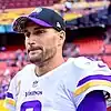 Headshot of Kirk Cousins wearing his uniform and a Minnesota Vikings hat