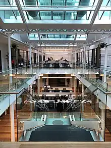 A coworking space on two levels with stairs and people working together. Underneath a big glass atrium