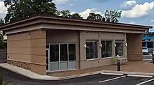 A small tan concrete building with a flat roof and a green sign saying "Curaleaf"