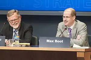 Max Boot sitting at a table on stage, with Henry R. Nau seated to his right, at the 2010 Current Strategy Forum at the Naval War College in Rhode Island.