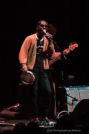 Harding singing on stage with a tambourine at his thigh