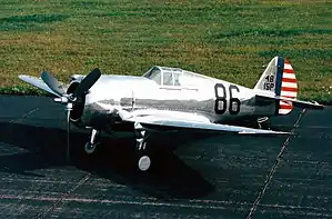 Shiny metal single-engine propeller-driven aircraft on a tarmac.